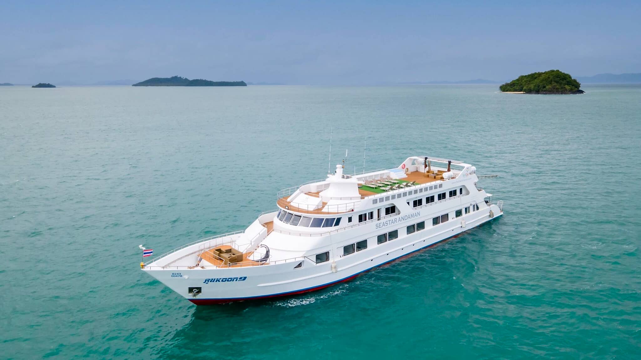 MV Koon 9 liveaboard on emerald water with limestone islands behind